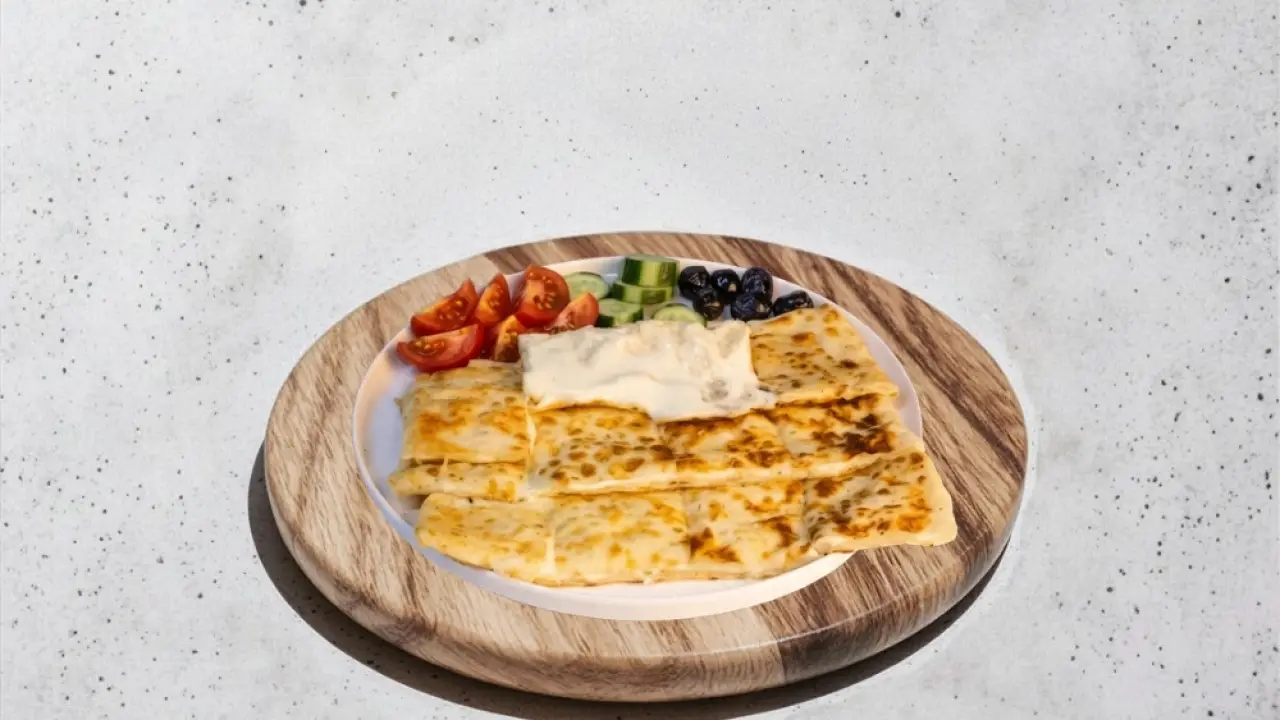 Ahşap sunum üzerinde domates, salatalık ve zeytinle servis edilen ballı peynirli gözleme